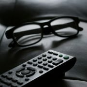 grayscale photo of remote beside eyeglasses