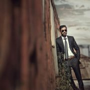 man in black suit standing on brown wooden bridge during daytime